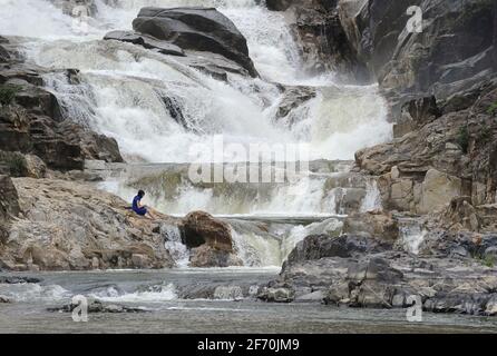 Tourist sitzt auf den Felsen am Ba Ho Wasserfall, Nha Trang, Vietnam Stockfoto