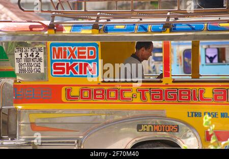 Filipino Jeeney auf Bohol Island, Central Visayas, Bohol, Philippinen. Jeepney-Dirigent in Jeepneys Fenster gerahmt. Stockfoto