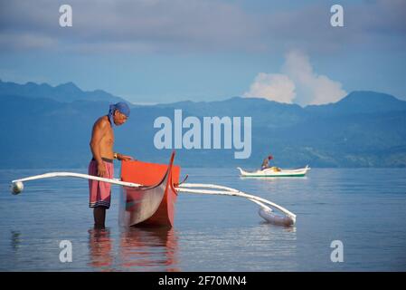 Der philippinische Fischer bereitet sich darauf vor, sein Auslegerkanu zu nehmen, um in der Visayan-See vor Moalboal, Cebu Island, Philippinen, zu fischen. Stockfoto