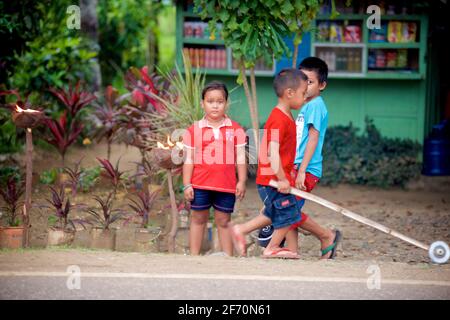 Kinder spielen auf der Straße, in der Nähe von Barili, Central Visayas, Cebu, Philippinen. Stockfoto