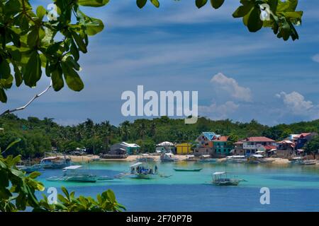 Logon, Malapascua Island, mit lokalen Booten, die in der Bucht festgemacht sind. Visayan Sea, Cebu, Philippinen. Stockfoto