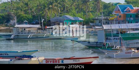 Logon, Malapascua Island, mit lokalen Booten, die in der Bucht festgemacht sind. Visayan Sea, Cebu, Philippinen. Stockfoto