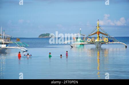 Logon, Malapascua Island, mit lokalen Booten, die in der Bucht festgemacht sind. Cebu, Philippinen. Schwimmen im Visayan Meer. Stockfoto