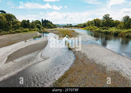 Der Tukituki River fließt durch die Stadt Waipukurau, Neuseeland. In der Ferne ist eine Eisenbahnbrücke zu sehen Stockfoto