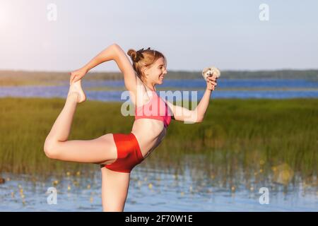 Die junge Frau, die Yoga-Tänzerin praktiziert, posiert im Sommer mit ihrem Igel auf grünem Gras im Park. Entspannen und Harmonie mit der Natur Stockfoto