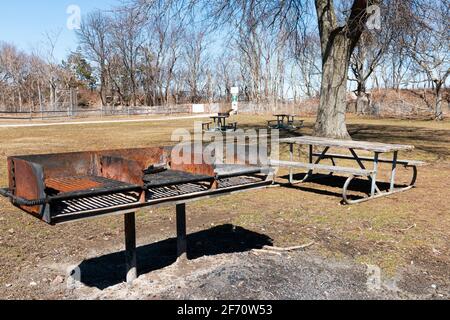 Dreifacher Grill im Sunken Meadow State Park mit Picknicktischen auf Gras. Stockfoto