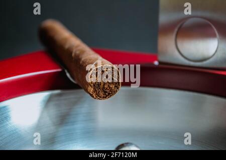 Nahansicht einer Zigarre auf einem Aschenbecher mit einem Cutter. Makroaufnahme Stockfoto