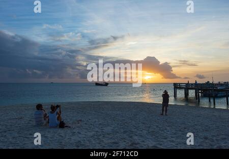 Tourist am Strand, der den Sonnenuntergang über dem Korallenmeer auf Heron Island, Southern Great Barrier Reef, Queensland, QLD, Australien, beobachtet Stockfoto