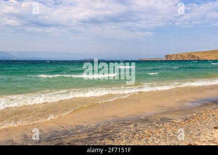 Schöner Panoramablick auf die mittleren Wellen am Baikalsee, Sandstrand und Wolken. Der wilde Strand befindet sich auf der Insel Olchon in der Region Irkutsk. Stockfoto