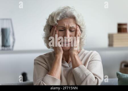 Verärgert erschöpfte reife 60s Frau, die unter Kopfschmerzen leidet Stockfoto