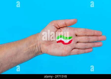 Auf dem ist eine grün-weiße und rote Flagge gemalt Handfläche einer Hand vor hellblauem Hintergrund Stockfoto