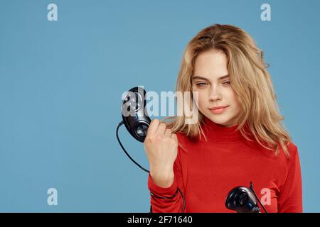 Hübsche Frau in rot Pullover Joystick Controller Set-Top-Box blau Hintergrund Stockfoto