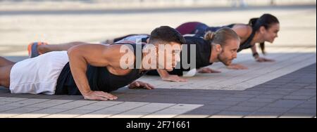 Gruppe von Fitness-Menschen tun Liegestütze in der Stadt Stockfoto