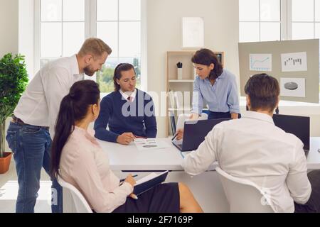 Abteilungsleiter führt ein Gespräch mit Mitarbeitern und analysiert Finanzberichte Im modernen Büro Stockfoto