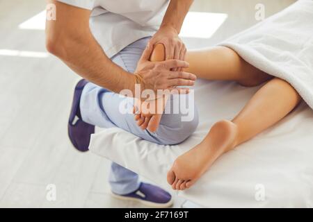 Professioneller Masseur tut Fußmassage für junge Frau in modernen Gesundheitsklinik Stockfoto