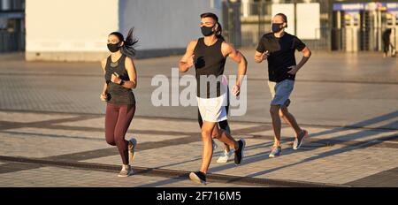 Athleten in schwarzen Schutzmasken joggen im Freien Stockfoto