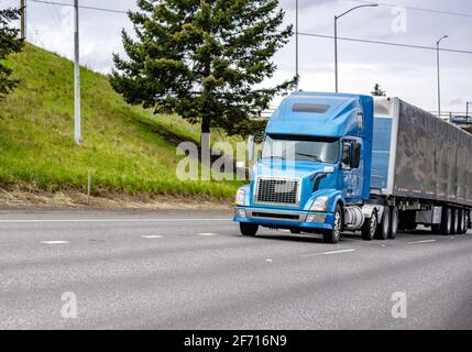 Kommerzielles großes Rig blau industriell grade Langstrecke professionelle semi LKW, der Ladung in einem trockenen Transporter transportiert, fährt weiter Das geteilte mehrzeilige Stockfoto
