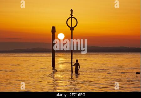 Portobello, Edinburgh, Schottland, UK Wetter. April 2021. Atemberaubender Sonnenaufgang am Ostersonntag am Meer, Temperatur 5 Grad Celsius. Im Bild: Ein junger Mann stellt seine Kamera auf und macht Selfie-Portraits am Strand Groyne am Firth of Forth. Stockfoto