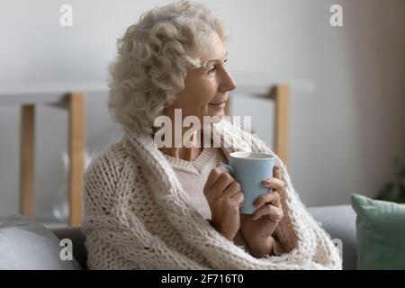 Glückliche nachdenkliche ältere Dame in Schal gewickelt Stockfoto