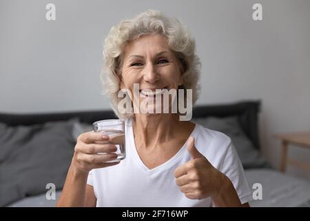 Porträt einer älteren Frau, die ihren Tag mit Trinkwasser beginnt Stockfoto