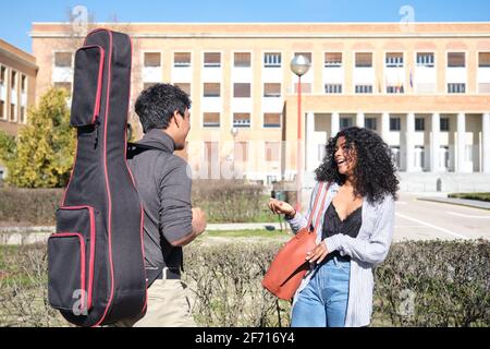 Lateinamerikanische Freunde sprechen auf dem College-Campus mit einem Gitarrenkoffer. Universitätsleben. Stockfoto