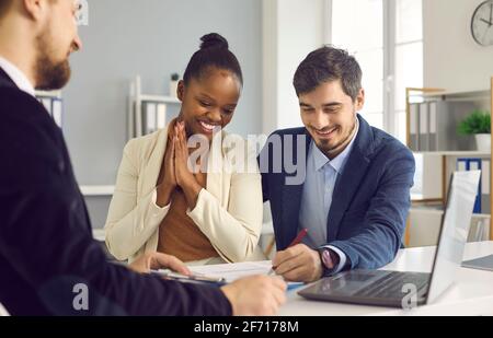 Frau sieht zu, wie ihr Mann im Büro einen Vertrag über die Vermietung oder den Kauf von Immobilien unterzeichnet. Stockfoto