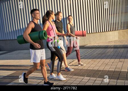 Glückliche Männer und Frauen mit Sportmatten und Springseil Stockfoto