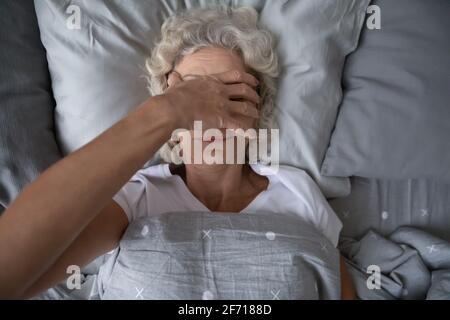 Friedliche, schlafende ältere Frau, die in ihrem Bett aufwachte Stockfoto