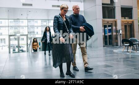 Leitende Geschäftsleute kommen ins Büro. Geschäftsmann und Geschäftsfrau gehen zusammen in der Lobby des Bürogebäudes. Stockfoto