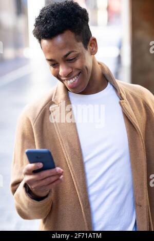 Junger schwarzer Mann mit seinem Smartphone im Freien. Stockfoto