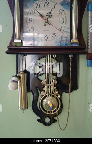 Alte hölzerne Pendeluhr mit Dekoration – Pferde mit Flügeln und anderen Details, die an einer Wand hängen, Vintage Wanduhr, Objekt Stockfoto