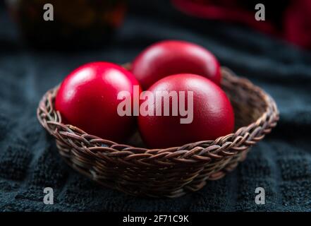 Eine Nahaufnahme von Ostereiern in einem Korbkorb, gefärbt in der traditionellen roten Farbe. Stockfoto