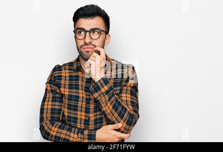 Hispanic Mann mit Bart tragen lässige Kleidung und Brille ernstes Gesicht denken über Frage mit der Hand auf dem Kinn, nachdenklich über verwirrende Idee Stockfoto