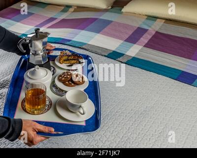 Ein köstliches Frühstück wird im Bett auf einem blauen serviert Fach Stockfoto