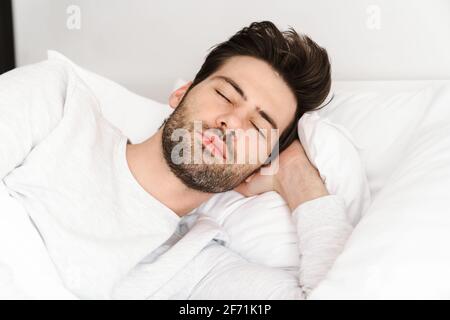 Friedlicher, hübscher junger Mann, der im Bett schläft und sich ausruht Zu Hause Stockfoto