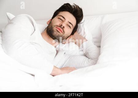 Zufrieden schöner junger Mann, der sich ausruhte und im Bett lag Zu Hause Stockfoto