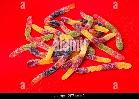 Gelee Würmer Süßigkeiten auf rotem Hintergrund. Stockfoto