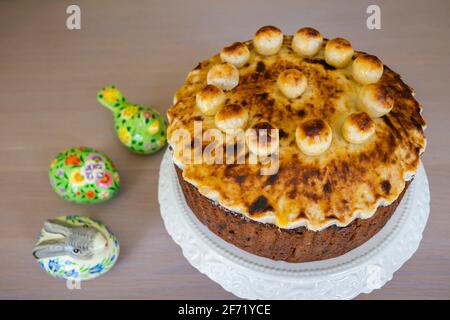 Ostergenuss: Ein ungeschnittener traditioneller, hausgemackter runder Simnellkuchen - Obstkuchen mit geröstetem Marzipan-Belag, verziert mit runden Marzipankugeln Stockfoto