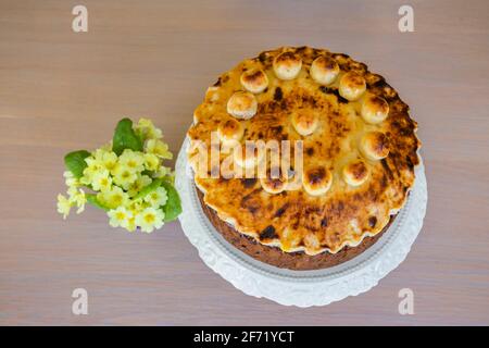 Ostergenuss: Ein ungeschnittener traditioneller, hausgemackter runder Simnellkuchen - Obstkuchen mit geröstetem Marzipan-Belag, verziert mit runden Marzipankugeln Stockfoto