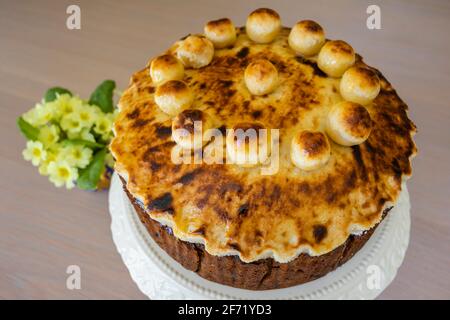 Ostergenuss: Ein ungeschnittener traditioneller, hausgemackter runder Simnellkuchen - Obstkuchen mit geröstetem Marzipan-Belag, verziert mit runden Marzipankugeln Stockfoto