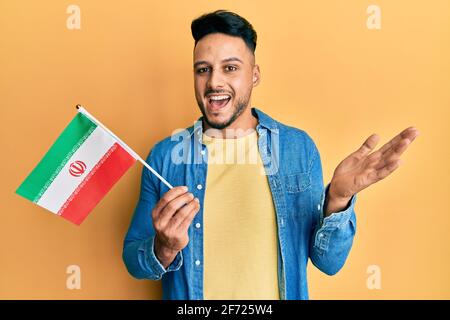 Junger araber mit iranischer Flagge feiert Erfolge mit Freude Lächeln und Ausdruck des Gewinners mit erhobener Hand Stockfoto