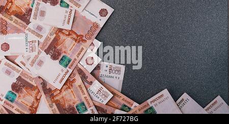 Russische Geldscheine von fünftausend Rubel, auf einem grauen Hintergrund verstreut, gibt es einen Platz für die Inschrift und den Text. Layout, Layout. Stockfoto