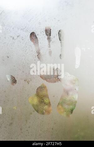 Der Abdruck der Handfläche der menschlichen Hand auf gefrorenem Fensterglas. Stockfoto