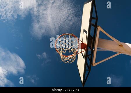 Leerer Basketballkorb aus niedrigerem Blickwinkel, heller, schöner Tag, offener Himmel. Ziele hoch/erreiche dein Zielkonzept. Stockfoto