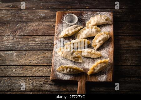 Asiatische rohe Knödel auf Holzschneidebrett. Traditionelle chinesische Dim Sum Knödel. Stockfoto