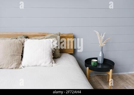 Schwarzer moderner Nachttisch neben dem Doppelbett mit Graue Bettwäsche in einem einfachen Schlafzimmer Stockfoto