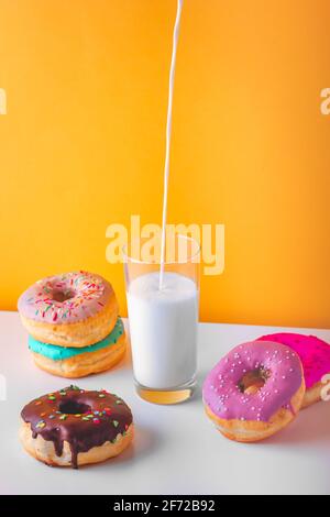 Süße Donuts mit einem Glas ausgiessende Pflanzenmilch Stockfoto