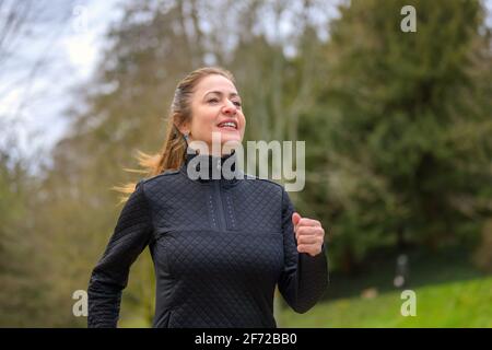 Fit Frau mittleren Alters genießen Joggen durch den Park in einem Nahaufnahme der unteren Körperansicht im Frühling in Ein gesundes Outdoor-Lifestyle-Konzept Stockfoto