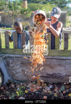 Primäre Alter kinder Entleerung Essensreste in die Komposttonne Stockfoto