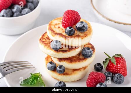 Hüttenkäse Pfannkuchen mit frischen Beeren, Tasse Kaffee und auf dem Tisch. Leckeres Frühstück - Bild Stockfoto
